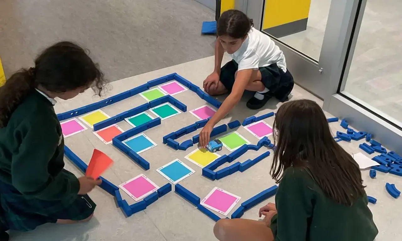 primary students setting up a maze on the floor out of blue blocks