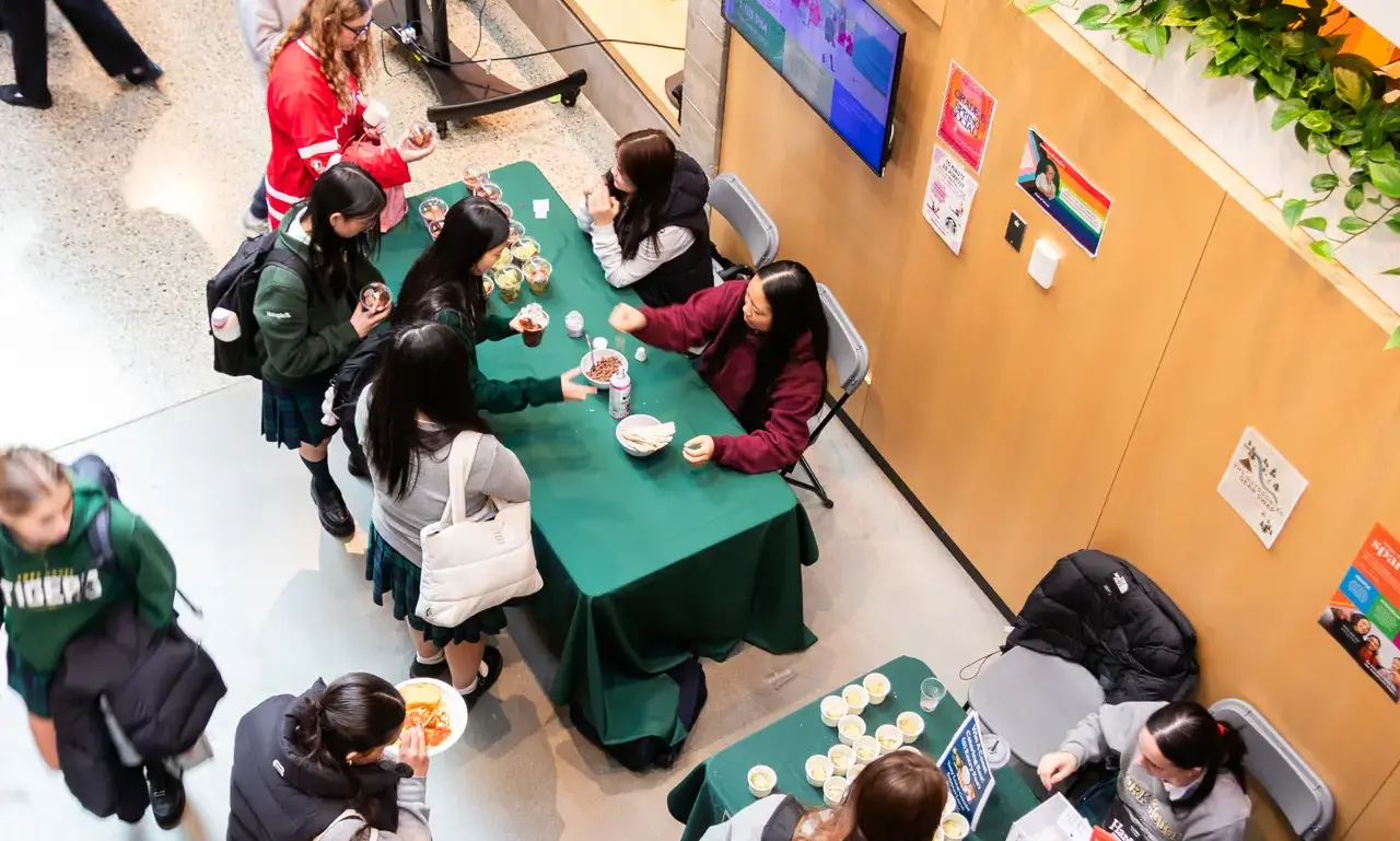 secondary entrepreneurship students sitting behind tables selling food to other secondary students